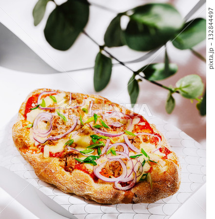 Delicious flatbread topped with cheese, vegetables, and herbs in a restaurant Delicious flatbread topped with cheese, vegetables, and herbs in a restaurant 132844497