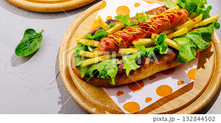 Delicious hot dog topped with lettuce, fries, and sauce at a casual dining spot Delicious hot dog topped with lettuce, fries, and sauce at a casual dining spot 132844502