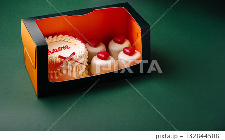 Delicious cake and pastries displayed in a colorful takeaway box Delicious cake and pastries displayed in a colorful takeaway box 132844508