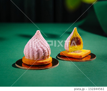 Two exquisite pastries sit elegantly on gold bases against a deep green surface Two exquisite pastries sit elegantly on gold bases against a deep green surface 132844561