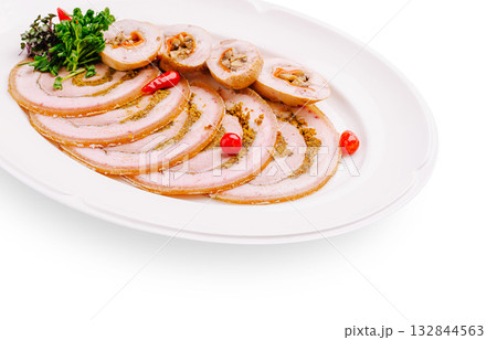 Sliced meat roll served on a white platter with herbs and chili 132844563