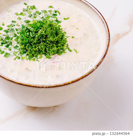 Creamy soup with fresh herbs in a rustic bowl on marble surface Creamy soup with fresh herbs in a rustic bowl on marble surface 132844564
