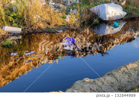 A canal is filled with dirty water and surrounded by garbage, highlighting serious pollution and ecological concerns in the area A canal is filled with dirty water and surrounded by garbage, highlighting serious pollution and ecological concerns in the area 132844989