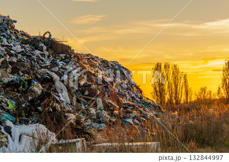 A sunset highlights a landfill filled with plastic debris and rubbish, illustrating the impact of waste on the environment and ecology A sunset highlights a landfill filled with plastic debris and rubbish, illustrating the impact of waste on the environment and ecology 132844997