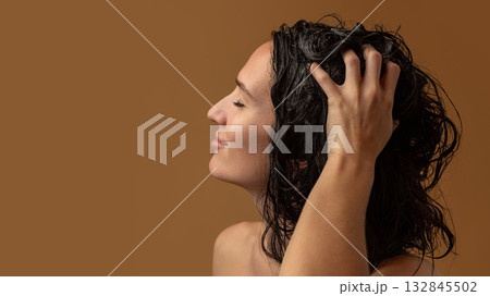 Woman massaging wet scalp with fingers during gentle hair washing 132845502