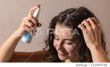 Woman applying hydrating scalp spray as part of home wellness hair treatment Woman applying hydrating scalp spray as part of home wellness hair treatment 132845536