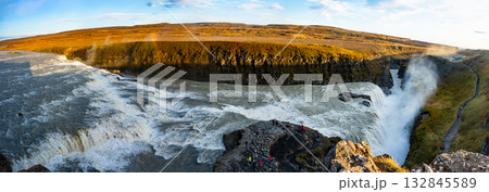 Gullfoss waterfall in Iceland showcases powerful cascades flowing into a canyon. Visitors admire the natural beauty from nearby viewpoints, especially during sunny weather. 132845589