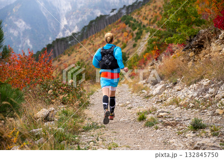Back view female athlete running mountain marathon in autumn 132845750