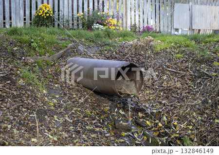 An old iron drain pipe with water leaking out of it An old iron drain pipe with water leaking out of it 132846149
