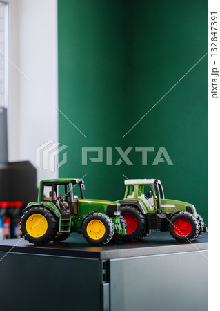 Toy tractors on modern desk in bright playroom, agriculture and kids transportation concept Toy tractors on modern desk in bright playroom, agriculture and kids transportation concept 132847391