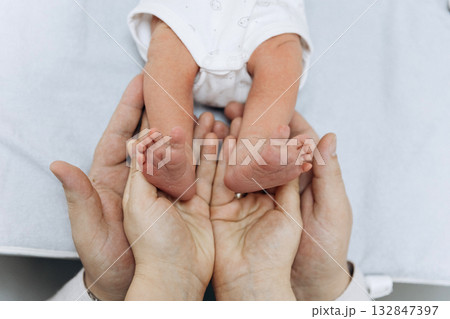 Newborn baby feet in parents hands symbolizing love, care and family protection 132847397