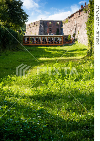 uzhhorod, ukraine - 08 aug 2012: grass in the old castle moat on a sunny afternoon. legendary landmark of transcarpathia under blue sky. medieval stronghold vertical travel background 132847617