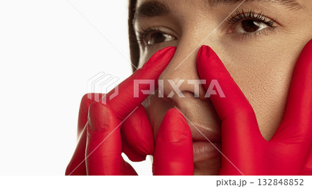 Closeup of woman face with red gloves touching nose before correction procedure Closeup of woman face with red gloves touching nose before correction procedure 132848852