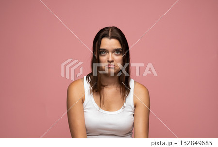 Studio portrait of young woman looking disappointed and upset showing sad face on pink background 132849685