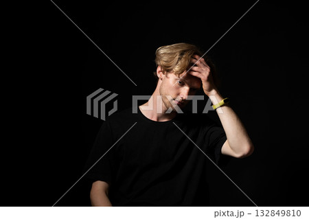 Regretful man in black shirt touching forehead with hand in low key dramatic portrait 132849810