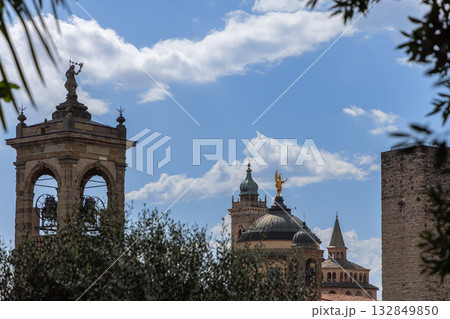 Iconic Bergamo towers including cathedral bell and Gombito rise framed by trees in sunny skyline Iconic Bergamo towers including cathedral bell and Gombito rise framed by trees in sunny skyline 132849850