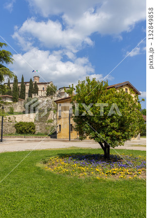View of Brescia Castle from Piazzale della Locomotiva framed by green lawn and warm sunlight glow View of Brescia Castle from Piazzale della Locomotiva framed by green lawn and warm sunlight glow 132849858