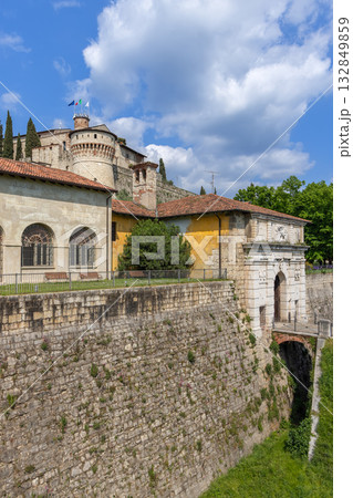 Massive stone walls and arched gateway of Brescia Castle rise below Torre dei Prigionieri tower Massive stone walls and arched gateway of Brescia Castle rise below Torre dei Prigionieri tower 132849859