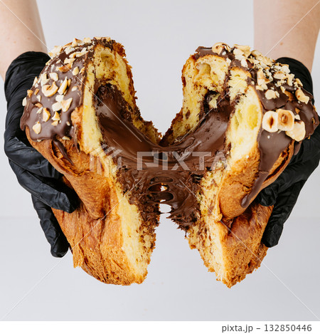 Hands in gloves breaking chocolate filled Christmas panettone, rich festive dessert 132850446
