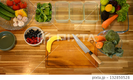 Above shot fresh vegetables and fruits neatly arranged in glass containers on a wooden kitchen counter, representing meal prep, food preservation 132850528
