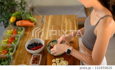 Female hands arranging fruits into a yogurt bowl, healthy breakfast concept with clean eating and wellness. 132850620