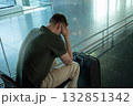 Young man with suitcase sitting in airport terminal looking upset, stressed and disappointed. Concept of flight delay, cancellation or travel problems. 132851342