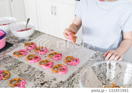 Freshly dipped and still glistening, these crunchy pretzels are lovingly adorned with pink chocolate and a scattering of colorful sprinkles, promising a feast for the senses. 132851981
