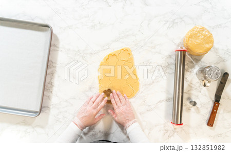 Hands pressing a flower-shaped cutter into cookie dough for Easter Cookie Sandwiches, preparing festive springtime treats with precision and care. Hands pressing a flower-shaped cutter into cookie dough for Easter Cookie Sandwiches, preparing festive springtime treats with precision and care. 132851982