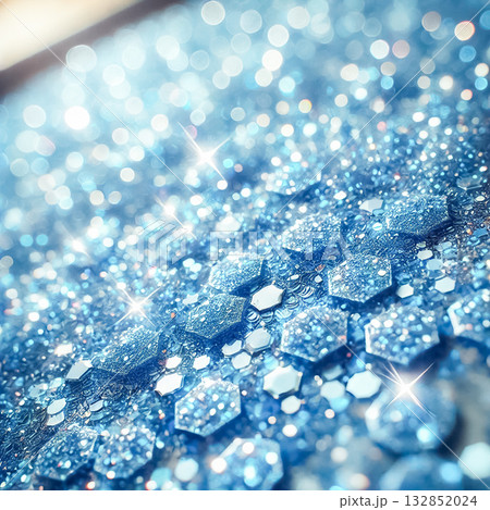 Light blue glitter particles, large and hexagonal, covering a surface from a low angle. The smooth, uniform texture features bright sky blue to light azure tones, with soft light reflections creating 132852024