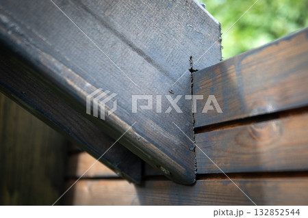 Detailed view of a wooden corner joint in an outdoor structure, highlighting texture, craftsmanship 132852544
