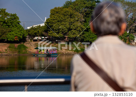 Senior woman looking at the river. Non motorized ferry, called planchon, used by residents to cross the Sinu River from one bank to the other in the city of Monteria, Colombia. 132853110