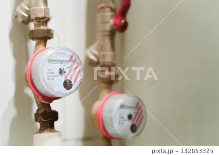 A detailed shot of a water flow meter connected to a pipe, measuring the amount of hot or cold water used for precise monitoring and efficient resource control. A detailed shot of a water flow meter connected to a pipe, measuring the amount of hot or cold water used for precise monitoring and efficient resource control. 132853325