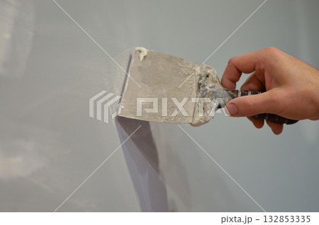 Construction worker - plastering and smoothing concrete wall with white cement by a steel trowel - spatula aligns Construction worker - plastering and smoothing concrete wall with white cement by a steel trowel - spatula aligns 132853335