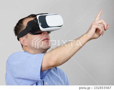 Man wearing virtual reality goggles on grey Man wearing virtual reality goggles on grey 132853567