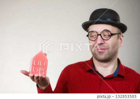 Man wearing funny eyeglasses holding house 132853583
