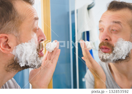 Guy shaving his beard in bathroom Guy shaving his beard in bathroom 132853592