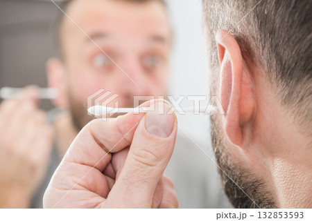Man removing wax from ear using Q-tip Man removing wax from ear using Q-tip 132853593