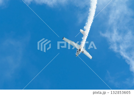 Stunt aerobatic plane performing stunts in blue sky with smoke trail. Concept of speed, difficulty, precision, risk, challenge Stunt aerobatic plane performing stunts in blue sky with smoke trail. Concept of speed, difficulty, precision, risk, challenge 132853605