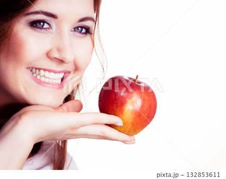 Woman holds apple fruit close to face, isolated Woman holds apple fruit close to face, isolated 132853611
