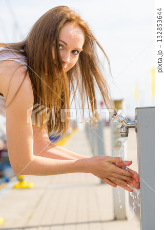 Woman drinking water from tap in marina. 132853644