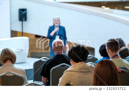 Speaker delivers talk to audience at conference in a bright modern atrium setting 132853722