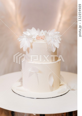 White angel feather christening cake with sleeping baby topper pastel background 132854989