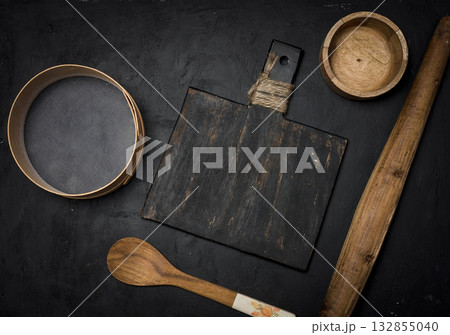 Set of vintage kitchen baking utensils wooden board, rolling pin, sieve and spoon on dark textured background. Set of vintage kitchen baking utensils wooden board, rolling pin, sieve and spoon on dark textured background. 132855040