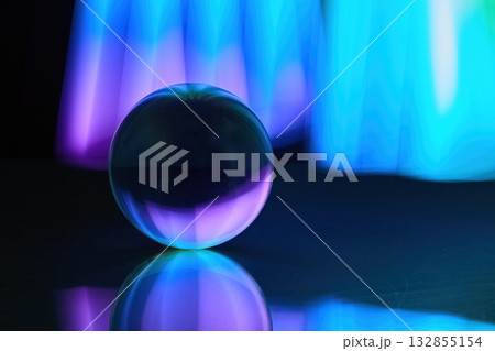 Mystic Sphere. A glowing glass sphere reflecting vibrant blue and purple lights in a dark setting. Mystic Sphere. A glowing glass sphere reflecting vibrant blue and purple lights in a dark setting. 132855154