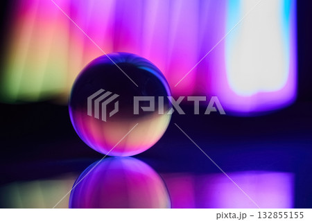 Vibrant Light Sphere. A glass sphere placed on a reflective surface with colorful light Vibrant Light Sphere. A glass sphere placed on a reflective surface with colorful light 132855155