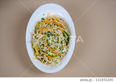 Cabbage carrot salad Fresh salad of white cabbage with carrots dressed with olive oil close-up in a bowl on the table. Vertical top view from above Cabbage carrot salad Fresh salad of white cabbage with carrots dressed with olive oil close-up in a bowl on the table. Vertical top view from above 132855200