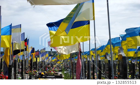 View on countless graves of ukrainian soldiers alley of glory in Kharkiv decorated with waving blue-yellow flags. The site commemorates soldiers who died during russian invasion in Ukraine. Slow mo 132855513