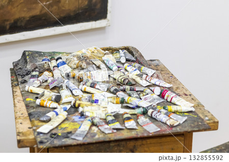 Artists workspace featuring a collection of used paint tubes and a well-worn wooden palette or table. 132855592
