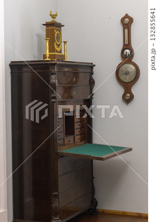 The image displays an antique secretary desk, also known as a secretaire or escritoire, which is a piece of furniture featuring a base of drawers and a hinged writing surface 132855641