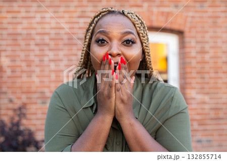 Surprised african american woman covering mouth with hands outdoors. Shock, amazement, and emotional spontaneity in expressive reaction. 132855714